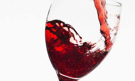 Close up of red wine being poured into glass on white background