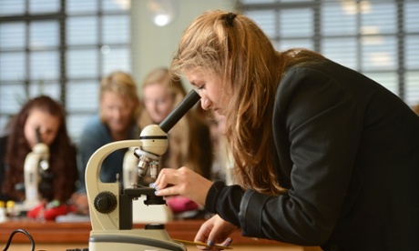 School girls using microscopes during a science lesson at Pates Grammar School in Cheltenham, UK