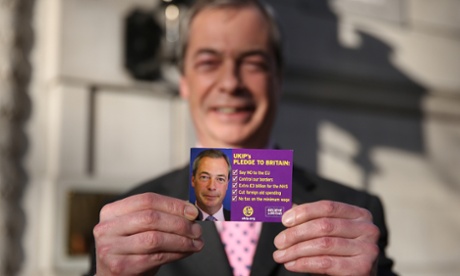 Nigel Farage holds up a pledge card as he arrives in Westminster