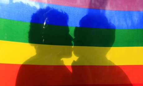 gay flag with two people kissing behind it 