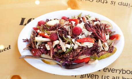 An oval plate of pear and berry salad with 'indeterminate white chicken protein', with a fork on it