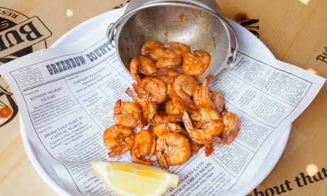 Shrimps spilling out of the horizontal metal-bucket Shrimper's Net Catch with a quarter of lemon