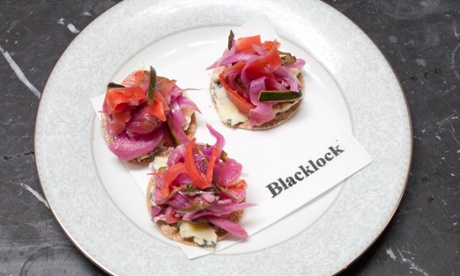 Three pink and red cheese and pickle crisp bites.