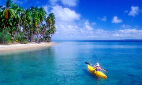 A woman sea kayaking near a tropical beach in Fiji.  Ocean cycles may have lulled us into a false sense of security by temporarily slowing global surface warming.