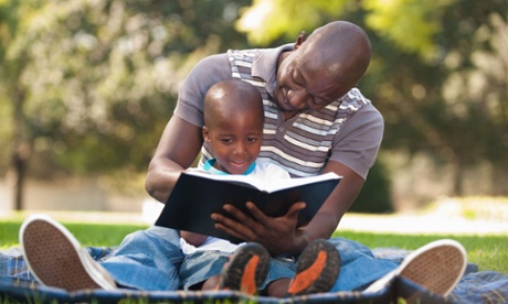 Father reading with son (4-5) on lawn, Johannesburg, Gauteng Province, South Africa
