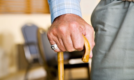An elderly man holding a walking stick.