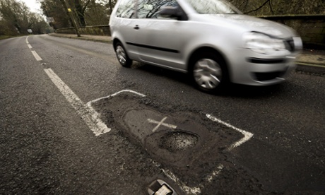 Car drives by a pothole