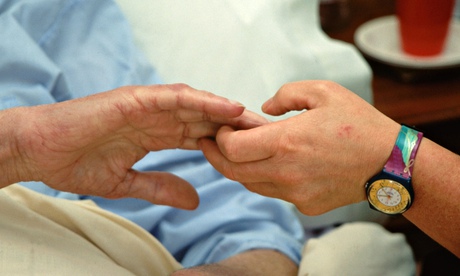 Hospice worker holding the hand of an elderly man