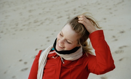 Young woman on a windy beach in a bright red jacket