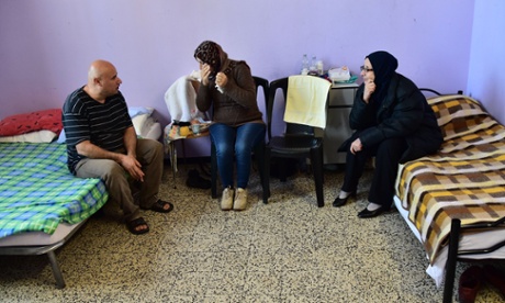Syrian migrants sit on beds at a refugee centre in Milan, Italy