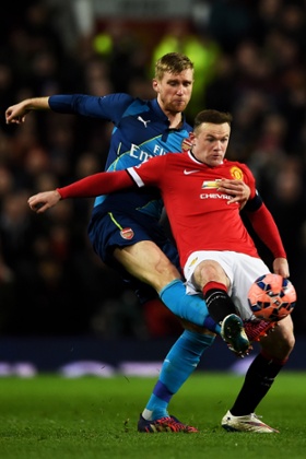 Per Mertesacker's long leg gets the better of Wayne Rooney.