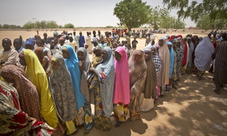 Nigerian women queue to cast their votes in the midday sun at a polling station in Daura.