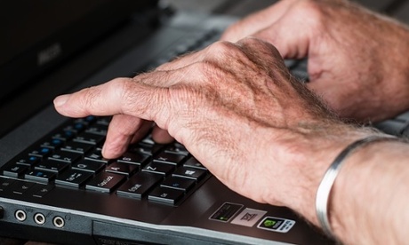 Old hands typing on a laptop