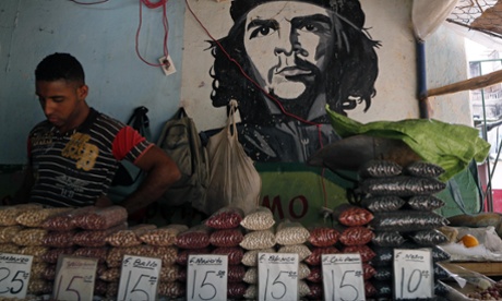 A man works at a bean stall at a market beside a mural with the a picture of revolution hero Ernesto ‘Che’ Guevara in Havana, Cuba.