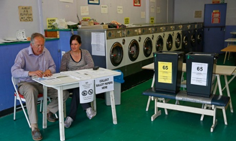 Poll clerks wait for voters in a public launderette being used as a polling station in Oxford.