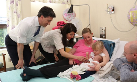 Ed Miliband and shadow health minister, Liz Kendall, talk to new parents Rebecca and Richard Booth with the Booths' newborn baby Mila and her sister Lola.