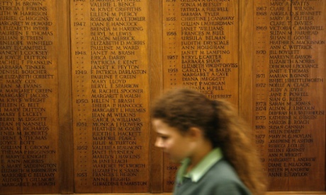 Young female pupil walks past a name plaque in a private school