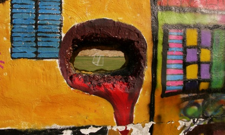 A hole in a wall reveals a football pitch inside the UN-controlled buffer zone dividing Nicosia