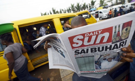 TOPSHOTS A man reads the Sun Daily newspapers with the headlines announcing the victory of the main opposition All Progressives Congress (APC) presidential candidate in Lagos, on April 1, 2015.  Nigeria's president-elect Muhammadu Buhari on April 1 praised the 