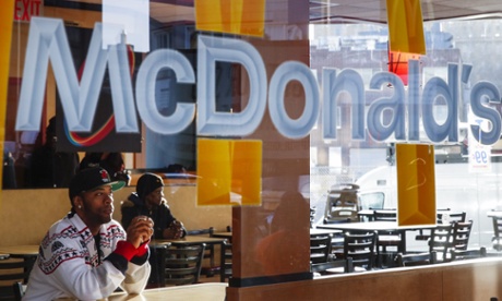 A man sits in a McDonald's restaurant and watches as protesters demonstrate for higher wages in the Brooklyn borough of New York City April 15, 2015. U.S. fast food workers fighting for better wages enlisted students, healthcare workers and racial justice activists to swell the ranks of rallies set for Wednesday in 230 cities.