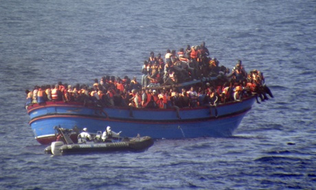 A motor boat from the Italian frigate Grecale approaches a boat overcrowded with migrants in the Mediterranean.