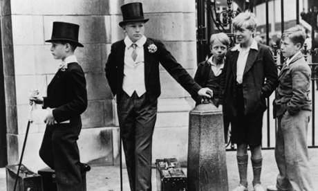 Hats off: a group of local boys look on with curiosity and amusement at Harrow schoolboys in their formal uniform before they play in the Eton vs Harrow cricket match.