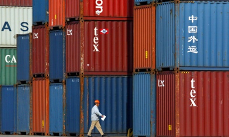 A Chinese worker walks past containers in Longwu Port in Shanghai