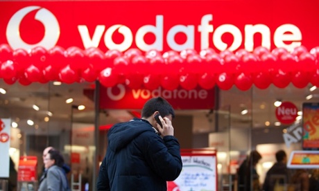 A pedestrian uses a mobile outside a Vodafone store