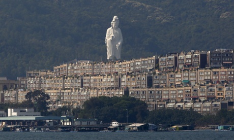 Tsz Shan monastery's bronze-forged white statue, stands behind luxurious houses at Taipo district in Hong Kong.