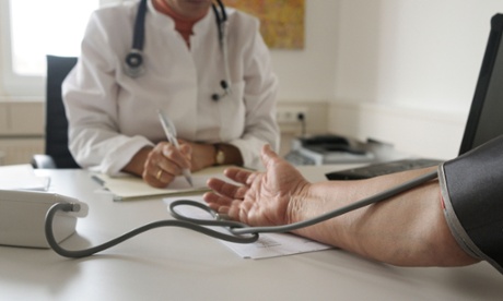 A GP takes the blood pressure of a patient