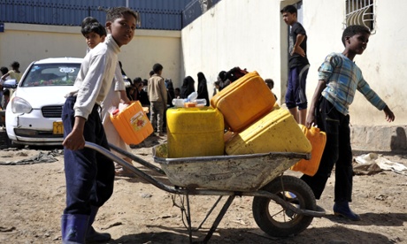 Yemeni children carry water at a supply center in Sanaa, Yemen