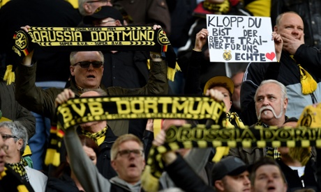 Dortmund supporters hold up scarves and a poster reading 