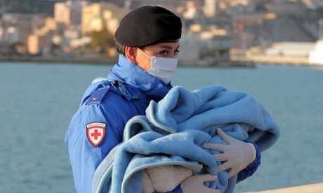A Red Cross officer carries a baby wrapped in a blanket after rescued migrants disembarked at the Sicilian port of Empedocle.