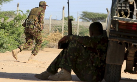 A Kenya Defense Force soldier runs for cover near the perimeter wall where attackers are holding up at a campus in Garissa.