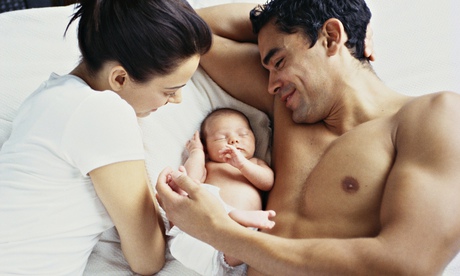 A couple lying with a newborn baby