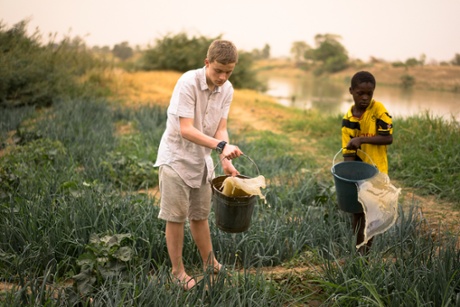 George helps Ayabil with the job of watering the family plot with buckets of water drawn from the river.