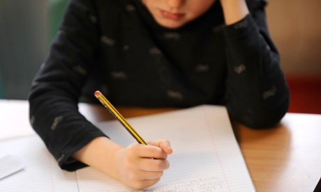 Child at a desk, putting pencil to paper 