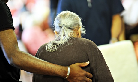 An elderly lady is helped to her chair in a care home.