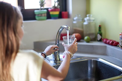Resident of Chilean neighbourhood fills water glass from faucet