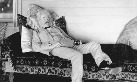 Mark Twain reclines on a sofa with a book.