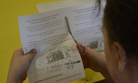Protester cuts out leaflets urging for the school to be saved.