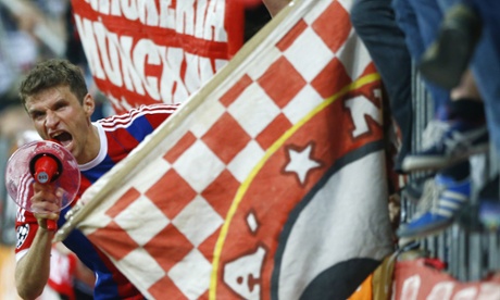 Bayern's Thomas Müller celebrates with the fans and a megaphone.