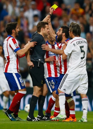 Arda Turan grabs the arm of referee Felix Brych as he is shown a second yellow card and is sent off.