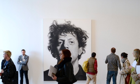 People walk past a Chuck Close portrait at the press preview.