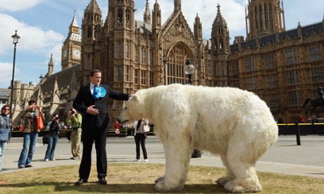 A David Cameron lookalike poses with a polar bear model outside the parliament as part of a Greenpeace protest