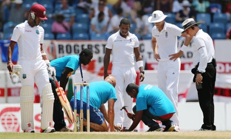 A member of the ground staff hammers nails into astroturf in an attempt to repair the pitch in Grenada.