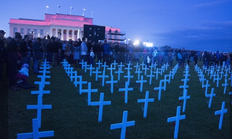 People stand behind crosses for the fallen at the Auckland War Memorial Museum on Anzac Day.
