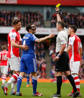 Cesc Fabregas is shown a yellow card for simulation by referee Michael Oliver.