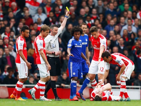 Referee Michael Oliver shows a yellow card to Willian after a challenge on Laurent Koscielny.