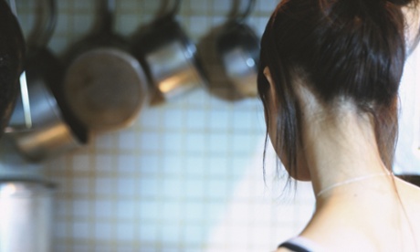 Young woman cooking in domestic kitchen, rear view